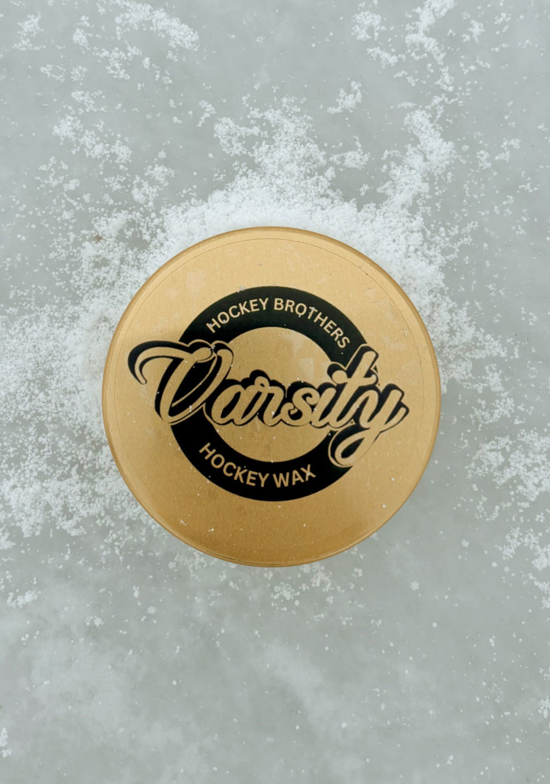 Our varsity hockey wax container laying on the ice surrounded by snow showing irony that our wax repels water.
