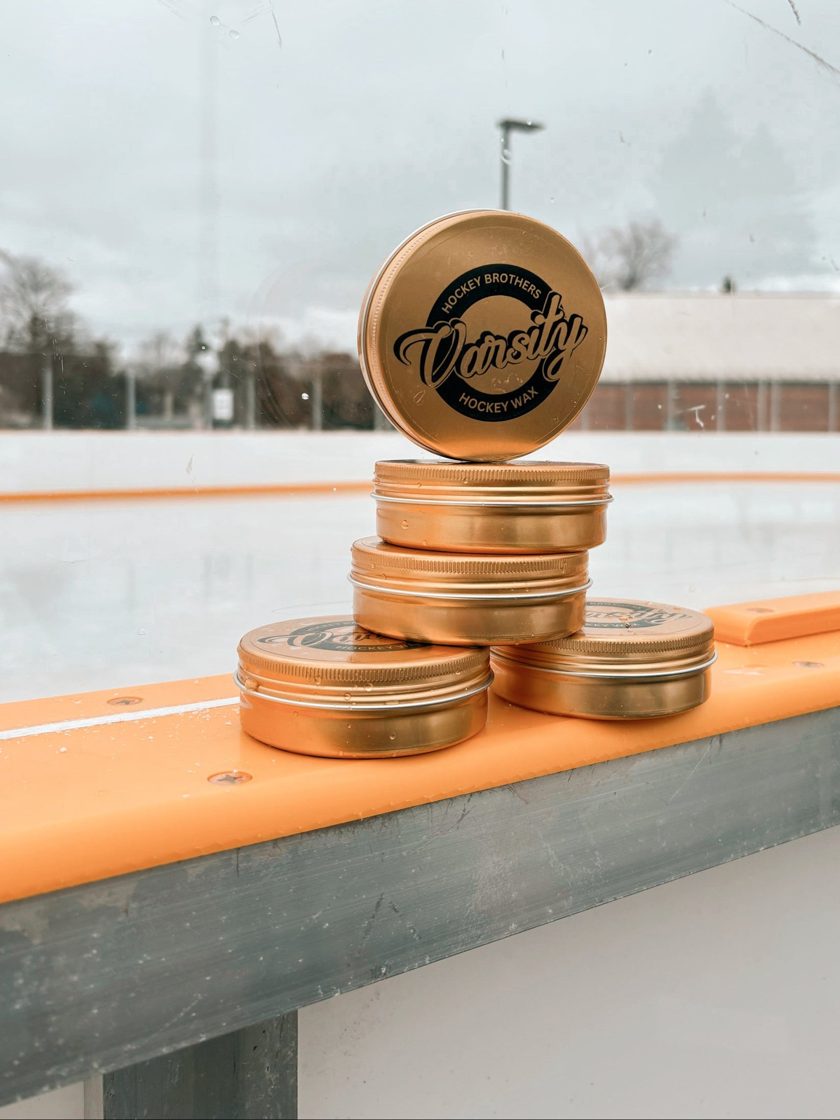 Varsity Hockey wax, the best quality wax on the market having s photoshoot up against the glass at an outdoor rink in Canada